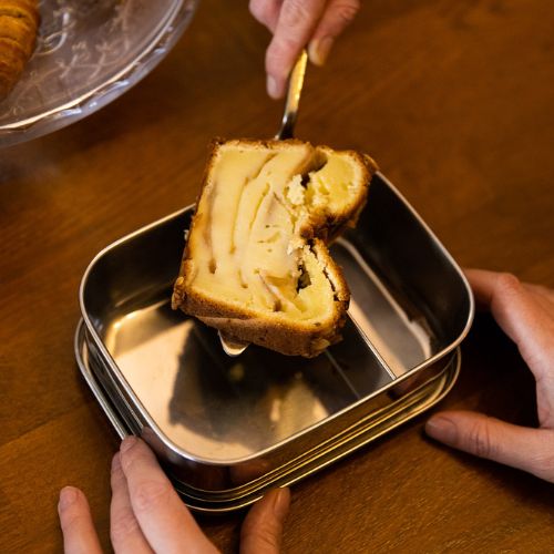 Foto eines Stücks Kuchen, das in eine Edelstahldose gelegt wird