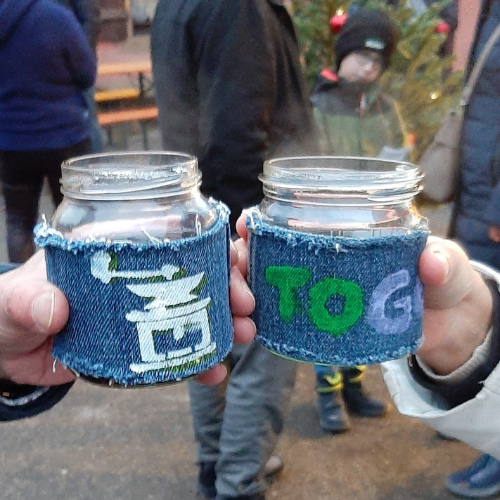 Zwei hochgehaltene Schraubgläser mit selbstgenähten Bechermanschetten