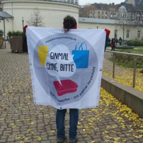 Foto von Katha vom Team Aachen hinter einem Banner von „Einmal ohne, bitte“