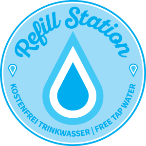 Blauer Kreis mit einem Wassertropfen in der Mitte und dem Text: „Refill-Station – kostenfrei Trinkwasser / free tap water“