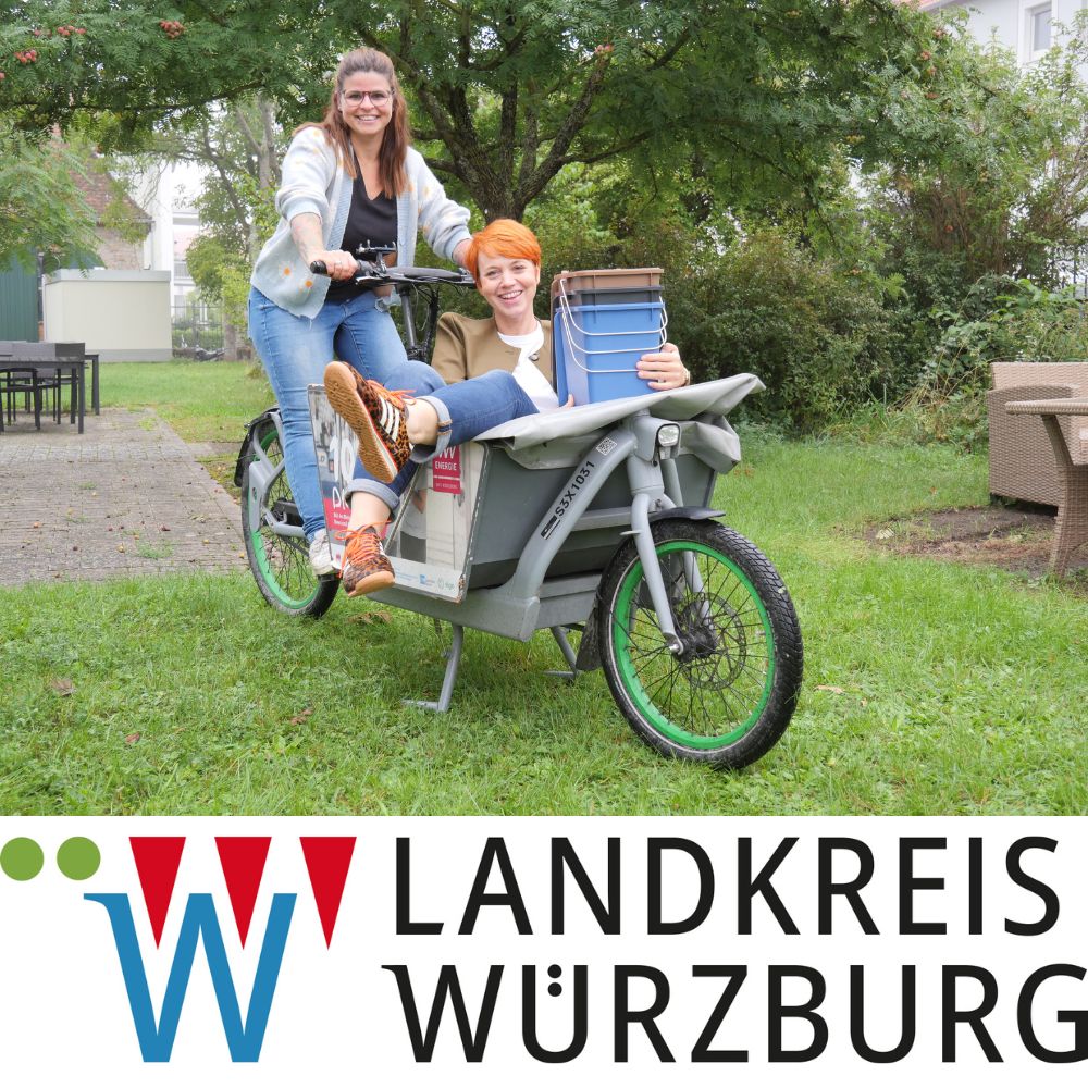 Rebecca-Michelle Walther und Maria Bethge von der Würzburger „Nachhaltigkeitsstunde“ mit Lastenrad; darunter das Logo vom „Landkreis Würzburg“