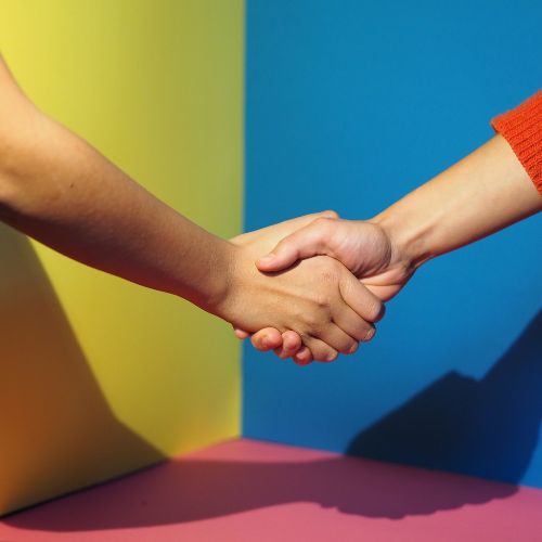 Foto eines Handschlags vor buntem Hintergrund als Symbolbild fürs Aktivwerden