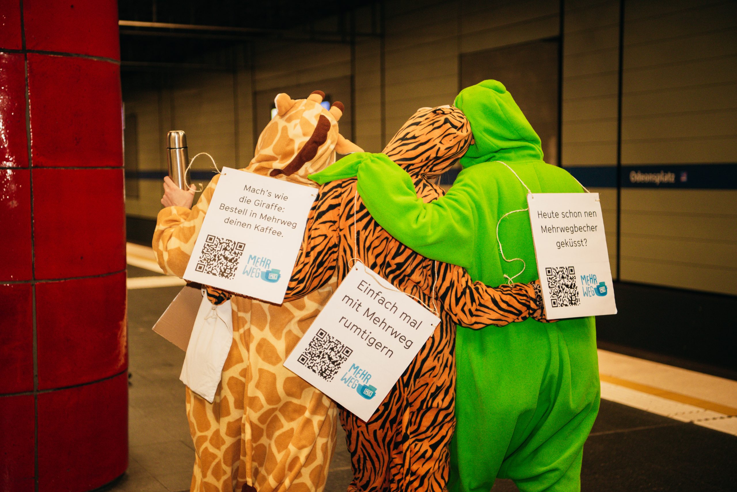 Foto von drei Personen in Tierkostümen und mit eigenen Behältnissen als „Mehrweg-Gang“ bei einer Sensibilisierungsaktion von „Mehrweg MUC“