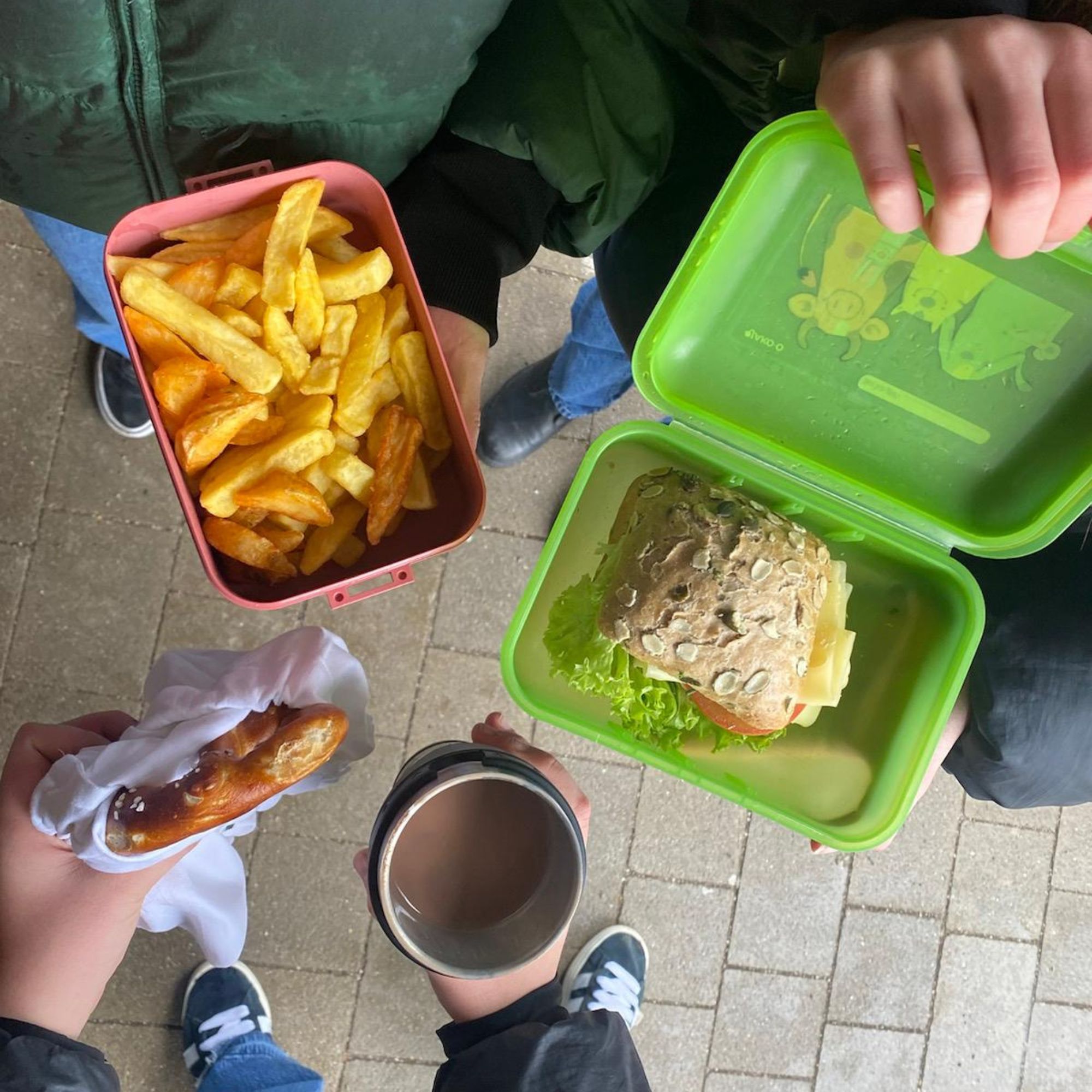 Foto von vier Kindern mit verschiedenen Speisen und Getränken in eigenen Behältnissen