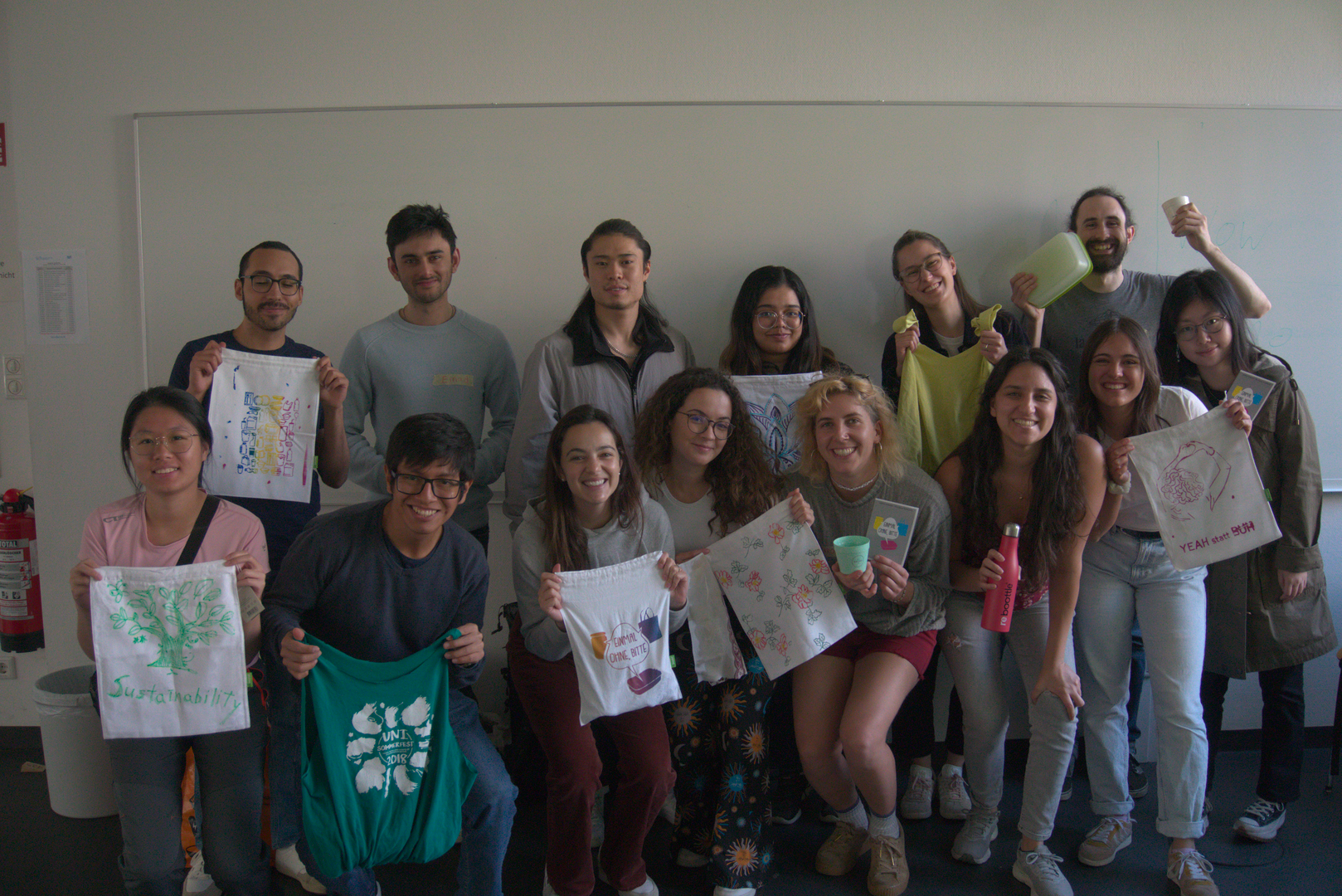 Gruppenfoto mit Studierenden, die Stoffbeutel und andere Workshop-Ergebnisse hochhalten