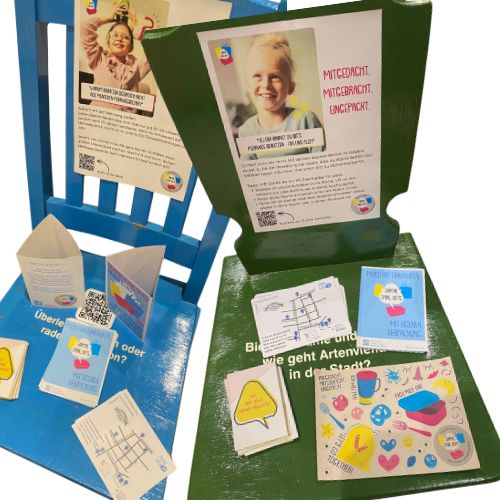 Foto von zwei bunten Stühlen, auf denen verschiedene Flyer ausliegen